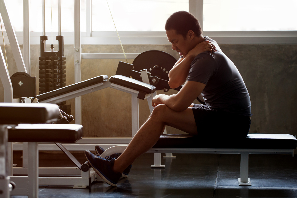 Man in the gym holding his shoulder in pain