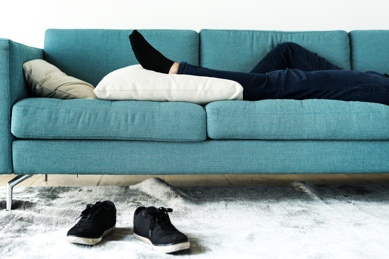 Man laying on sofa with his leg elevated due to leg pain from a car accident