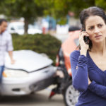 Female Driver Making Phone Call After Traffic Accident With Crash In Background.