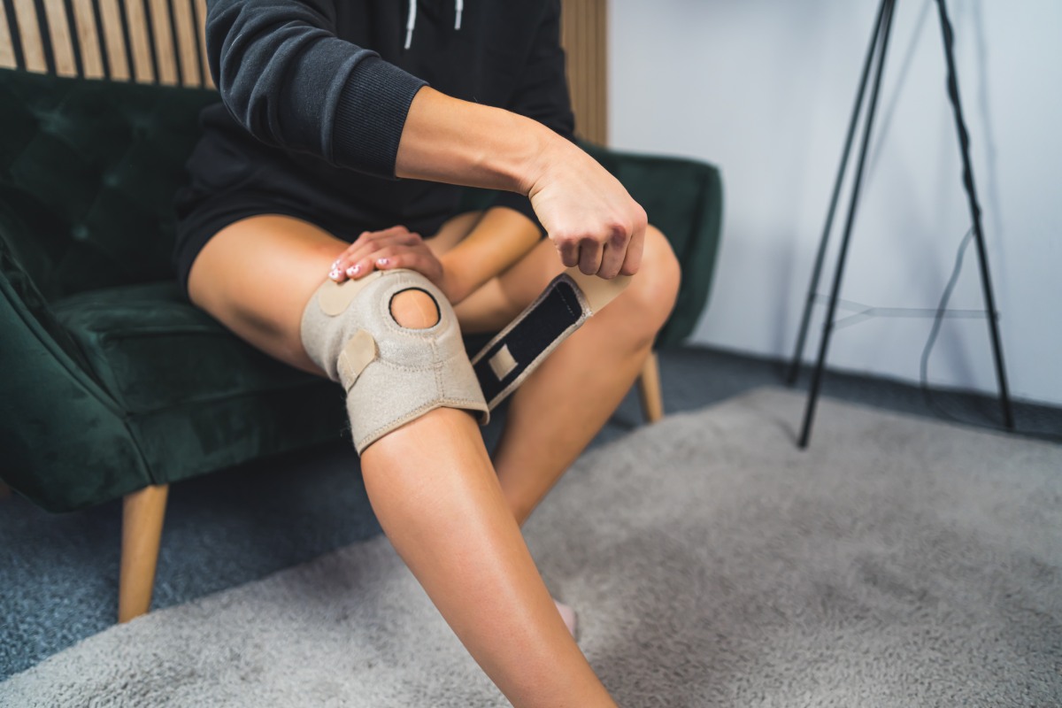 A woman wearing a knee brace post acl surgery.