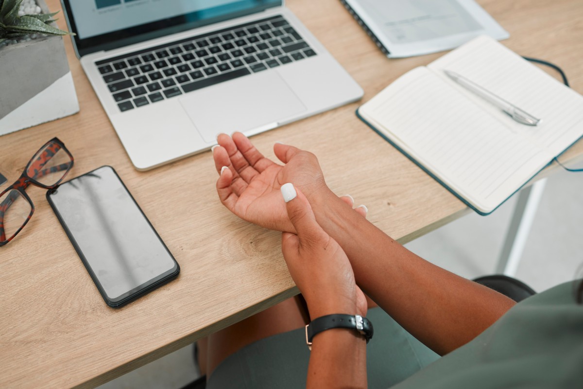 A woman at her computer massaging the carpal tunnel in her wrist