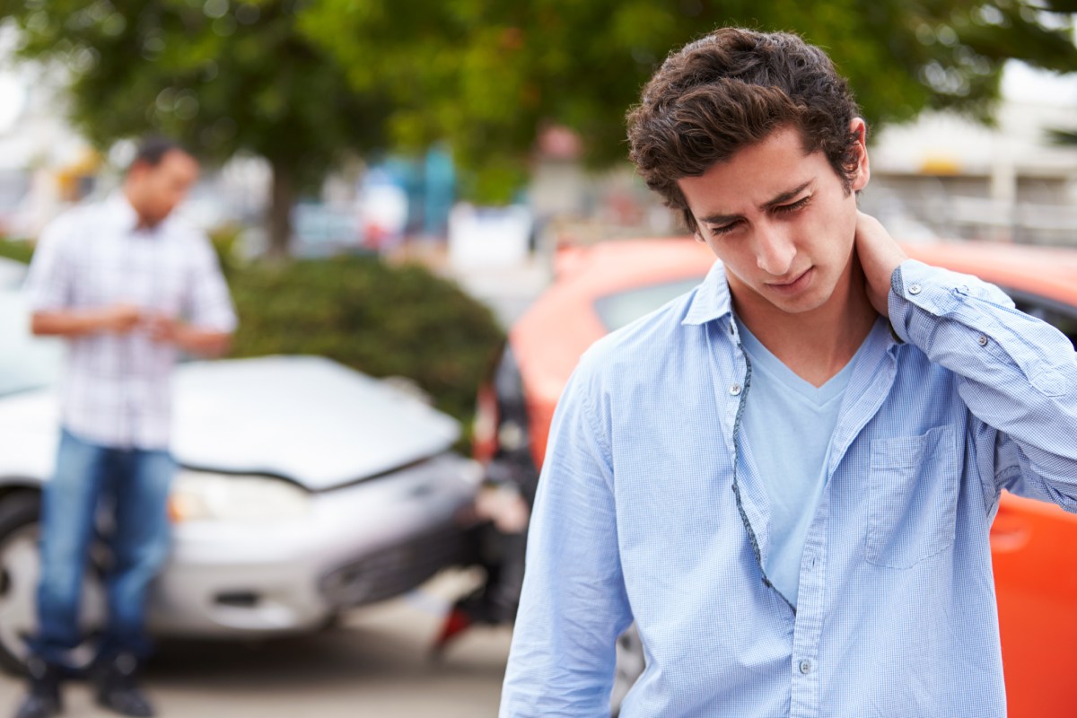 A young man grabbing his neck in pain after a car accident.