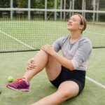 Tennis player on the ground in pain with ACL tear injury.