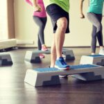 Exercise group performing step-ups onto a platform to strengthen their knees.