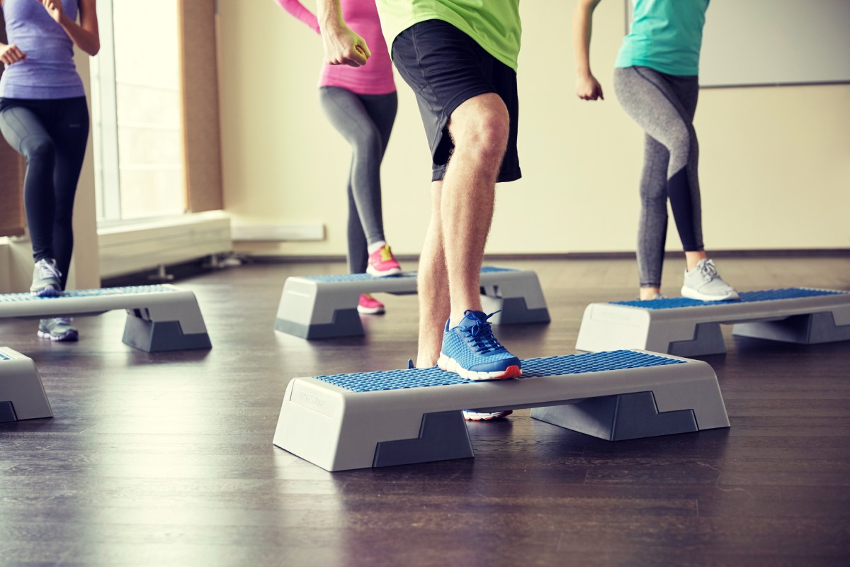 Exercise group performing step-ups onto a platform to strengthen their knees.