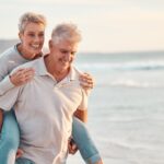 Older couple walking on beach after knee replacement surgery.