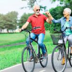 Active older couple riding bicycles and smiling in a park, symbolizing improved mobility after hip surgery recovery time.