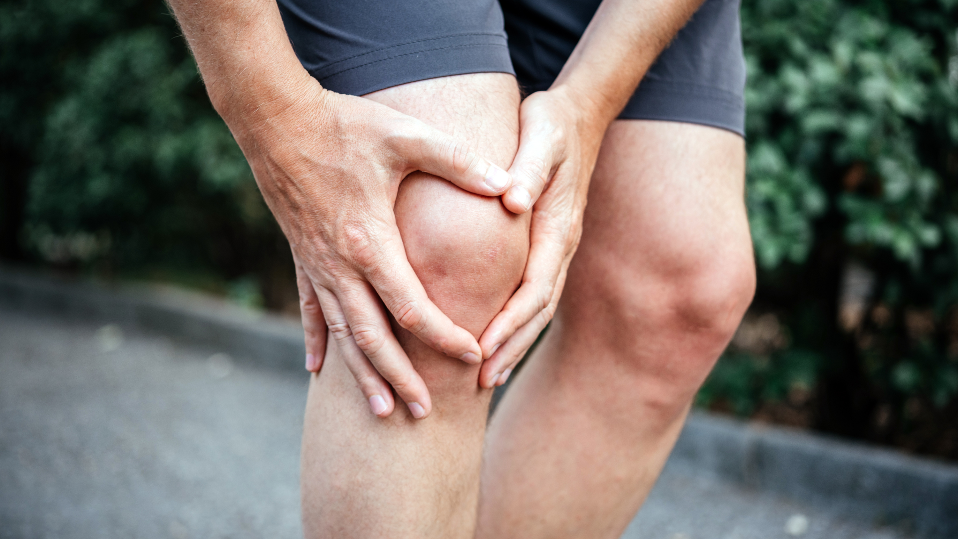 Person holding a swollen, reddened knee, illustrating common meniscus tear symptoms such as swelling, pain, and tenderness.